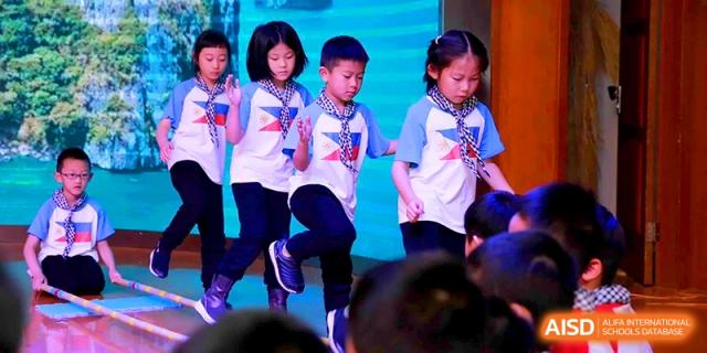 Students in white shirts and blue scarves participate in a rhythmic group activity at Shanghai United International School, Shangyin Campus.