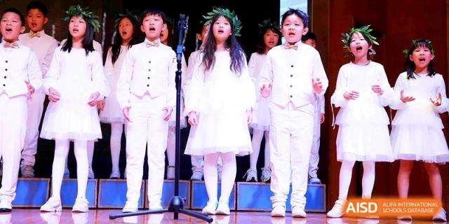 A student choir dressed in formal white attire performs a choral piece at Shanghai United International School, Shangyin Campus.
