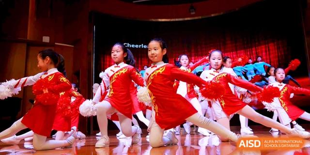 Young cheerleaders in bright red outfits perform an energetic dance routine at Shanghai United International School, Shangyin Campus.