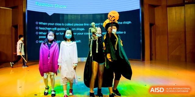 Students in creative Halloween costumes pose on stage for a festive event at Shanghai United International School, Shangyin Campus.
