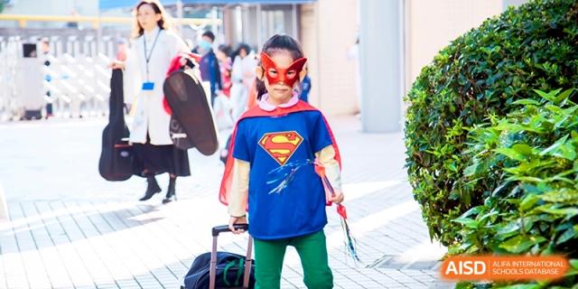 A young student wearing a Supergirl costume and mask smiles for a photo at Shanghai United International School, Shangyin Campus.