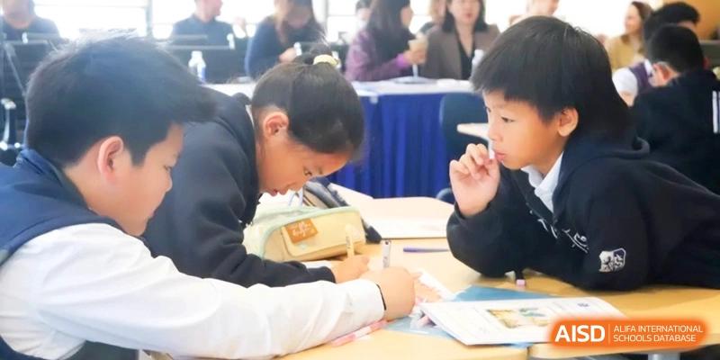 Students work together on a writing assignment during a classroom session with focused expressions at Shanghai United International School, Qingpu Campus