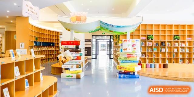A colorful library entrance with book-shaped pillars and open shelves creates an inviting reading space at Shanghai United International School, Qingpu Campus