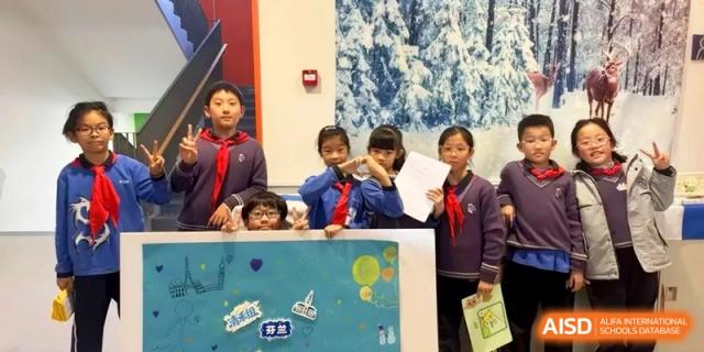 Happy students in school uniforms pose together with their creative projects against a winter-themed backdrop at Shanghai United International School, Qingpu Campus
