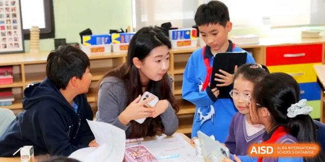 A teacher provides personalized guidance to a student using a digital tablet during a collaborative lesson at Shanghai United International School, Qingpu Campus