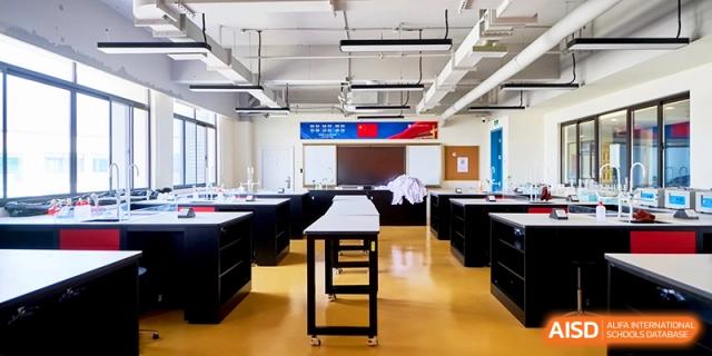 A clean and spacious science laboratory is equipped with black workstations and stools for practical learning at Shanghai United International School, Qingpu Campus
