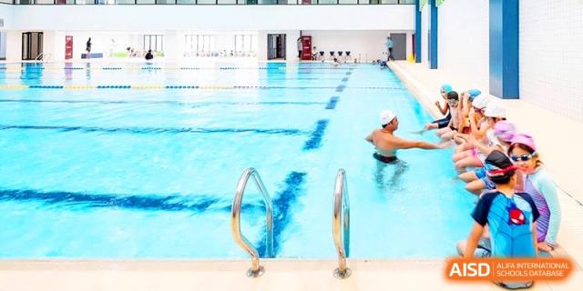A clear blue indoor swimming pool with marked lanes provides a professional space for student athletics at Shanghai United International School, Qingpu Campus