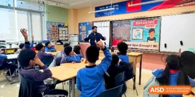Students in a classroom raise their hands during a lesson with a teacher at Shanghai United International School,Qingpu Campus
