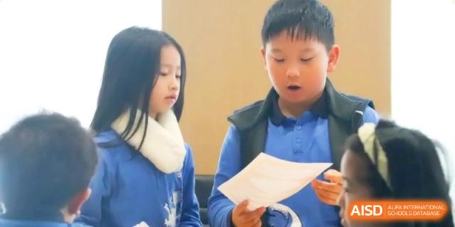 Two young students focus on reading a paper document together at Shanghai United International School,Qingpu Campus
