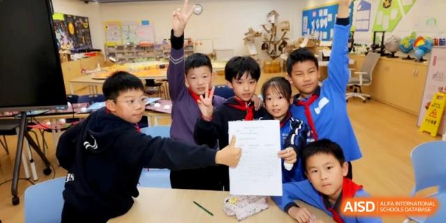 Group of smiling students holding up a certificate or paper in class at Shanghai United International School,Qingpu Campus