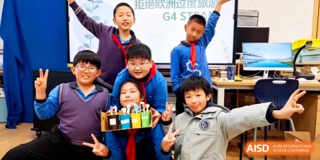 Group of happy students posing together for a photo in their classroom at Shanghai United International School,Qingpu Campus