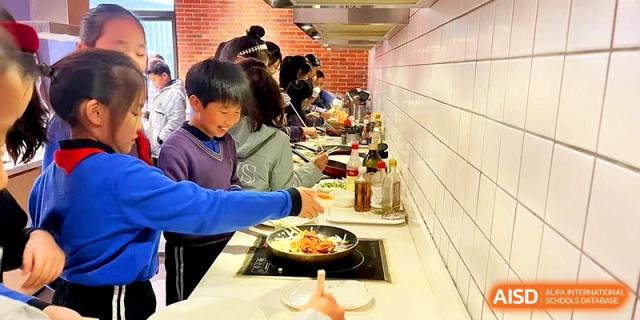 Students participate in a hands-on culinary arts class, preparing food at a professional cooking station at Shanghai United International School,Qingpu Campus.