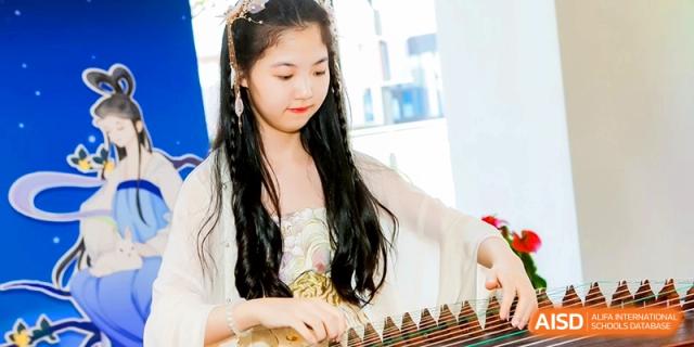 A student dressed in traditional attire plays the Guzheng with precision during a musical performance at Shanghai United International School,Qingpu Campus.