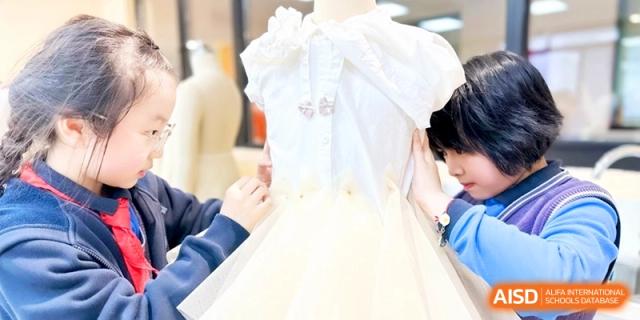 Detailed view of students collaborating on a fashion design project, pinning fabric on a dress form at Shanghai United International School,Qingpu Campus.