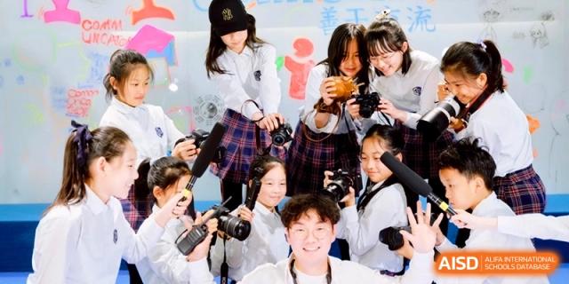 A group of students practicing media skills by holding cameras and microphones during a journalism workshop at Shanghai United International School,Qingpu Campus.