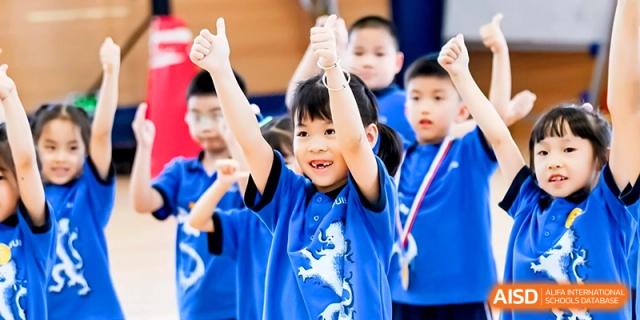 A happy student in a blue school uniform cheers with thumbs up during an outdoor sports day celebration at Shanghai United International School,Qingpu Campus.