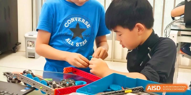 Two young students collaborating on a hands-on STEM project using building blocks and colorful tools at HT Nanjing Impact Academy.
