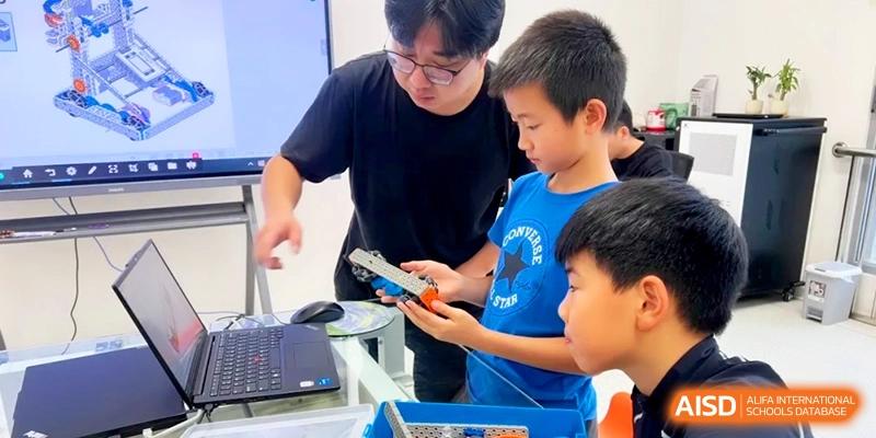 A teacher providing guidance to students as they work on a complex robotics and engineering project at HT Nanjing Impact Academy.