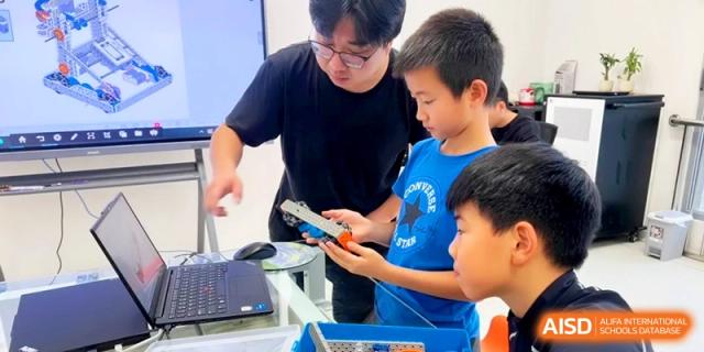 A teacher providing guidance to students as they work on a complex robotics and engineering project at HT Nanjing Impact Academy.