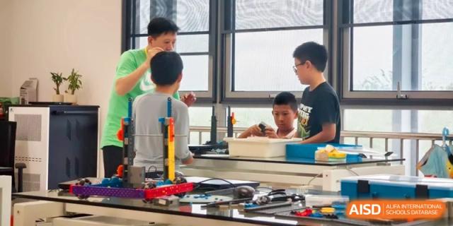 Students working together in a science lab setting with various technical equipment and learning materials at HT Nanjing Impact Academy.