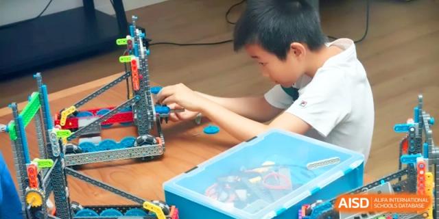 A student focused on building and assembling a technical robotics model during a hands-on workshop at HT Nanjing Impact Academy.