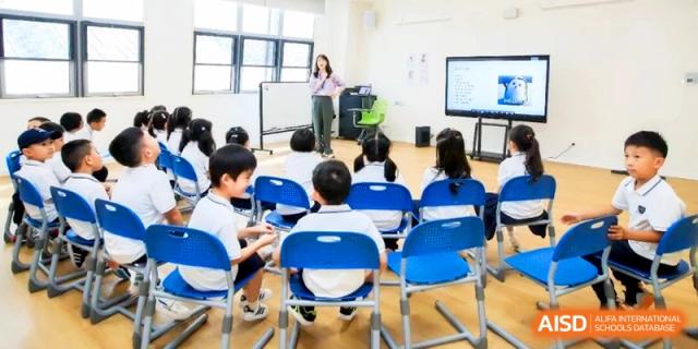 A teacher standing at the front of a classroom addressing a group of students seated at their desks at HT Nanjing Impact Academy.
