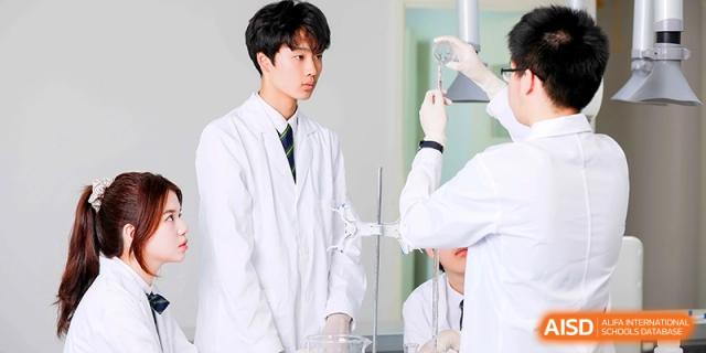Students in white lab coats conducting a science experiment with glassware in a bright, modern laboratory at HT Nanjing Impact Academy.