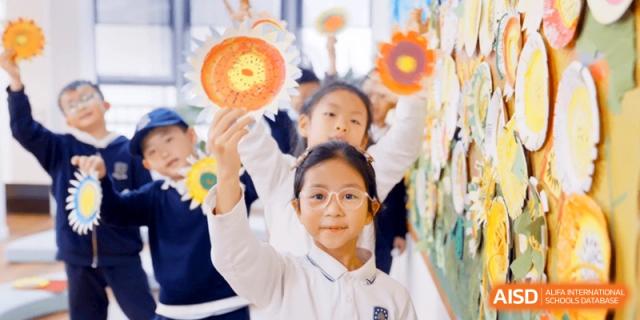 A young student holding up a bright orange, handcrafted sun during an art and crafts workshop at HT Nanjing Impact Academy.