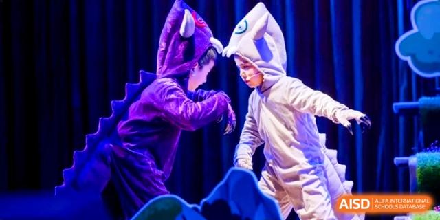 Two students in animal onesies performing a playful skit during a school play or cultural festival at HT Nanjing Impact Academy.