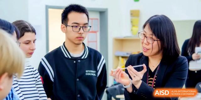 A student council member in a school jacket works on a project with a teacher’s guidance at the International School of Tianjin.