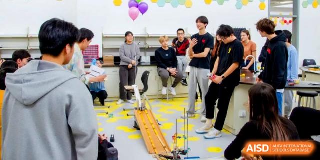 Students gather around a wooden ramp for a physics experiment in a bright science lab at the International School of Tianjin.