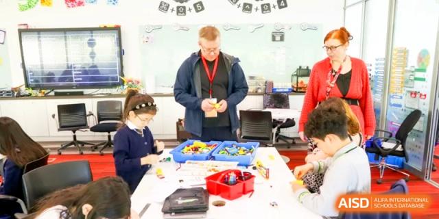 A teacher assists a student with a tabletop activity using small plastic containers at the International School of Tianjin.