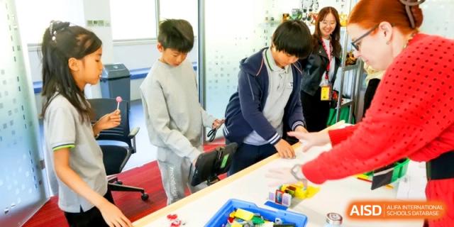 Two students work together on a hands-on building project using colorful blocks at the International School of Tianjin.