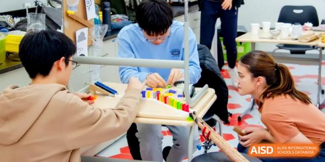 A student carefully assembles a row of colorful blocks as part of a classroom activity at the International School of Tianjin.