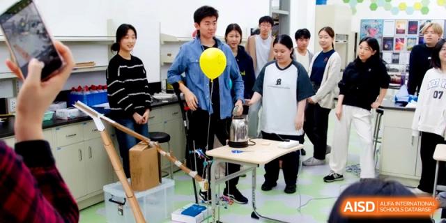 A student conducts a science experiment involving a yellow balloon and a kettle in a lab at the International School of Tianjin.