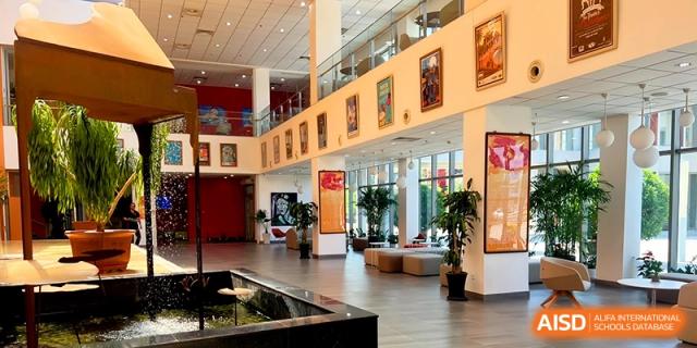 The spacious, multi-level atrium and lobby area featuring indoor plants and art at the International School of Tianjin.