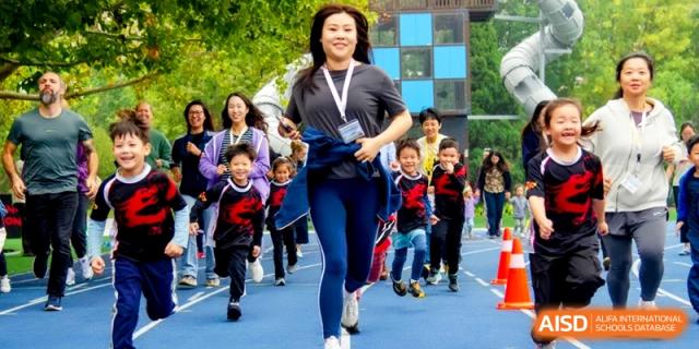 A teacher and young students participate in a spirited outdoor fun run on the blue track at the International School of Tianjin.
