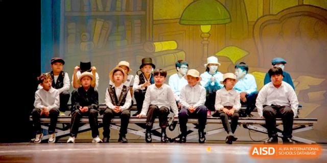 Primary students in costumes perform a play together on a professional stage at the International School of Tianjin.