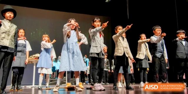 A group of girls in costume perform a synchronized dance routine on stage at the International School of Tianjin.