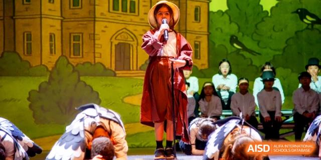 A solo performer in a hat and period costume sings a song during a school play at the International School of Tianjin.