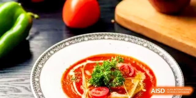 A bowl of gourmet tomato soup garnished with fresh cream and herbs served at the International School of Tianjin.