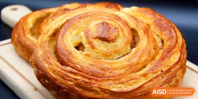 A freshly baked, golden-brown cinnamon swirl pastry with flaky layers at the International School of Tianjin.
