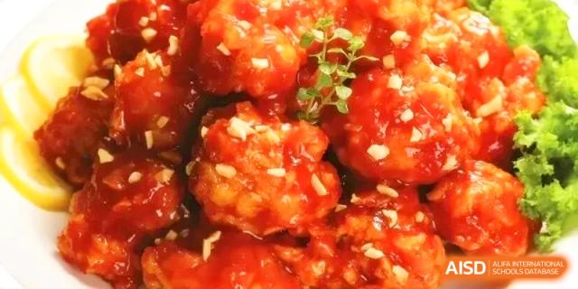 Close-up of sweet and sour crispy chicken pieces with a glossy red glaze at the International School of Tianjin.