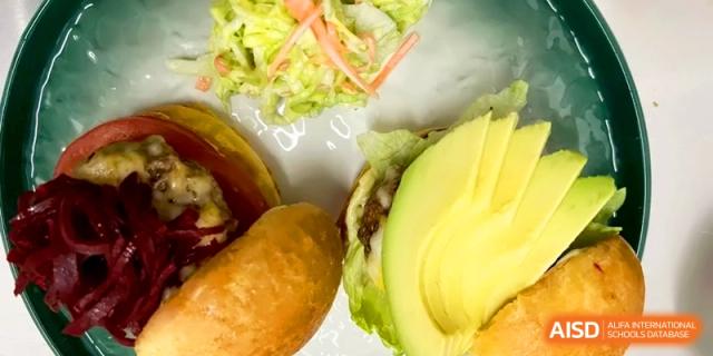 A healthy burger topped with fresh avocado slices and crisp lettuce at the International School of Tianjin.