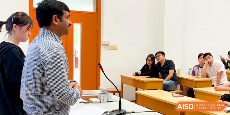 A male instructor speaks to students seated at desks in a bright classroom during a meeting at Xishan Senior High School.