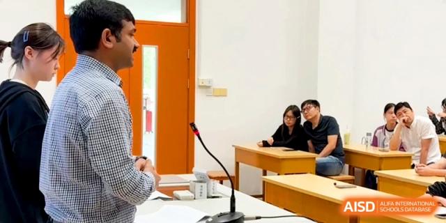 A male instructor speaks to students seated at desks in a bright classroom during a meeting at Xishan Senior High School.