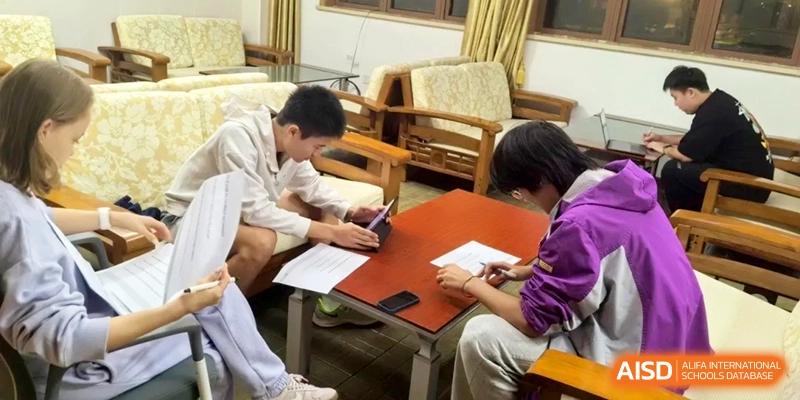 Two students sit at a table in a lounge area while working on tablets and reviewing documents at Xishan Senior High School.