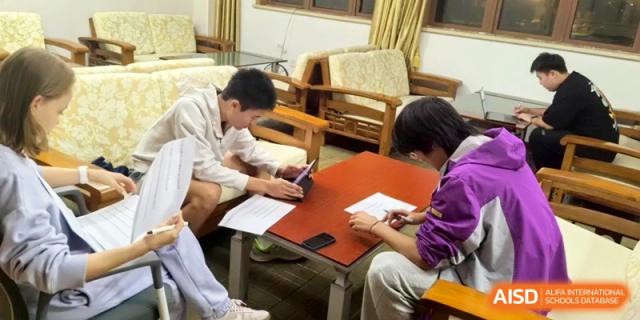 Two students sit at a table in a lounge area while working on tablets and reviewing documents at Xishan Senior High School.