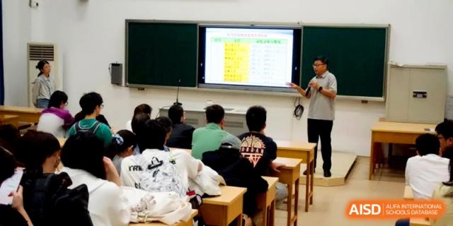 A male teacher points to a data table on a large digital screen while lecturing a class of students at Xishan Senior High School.
