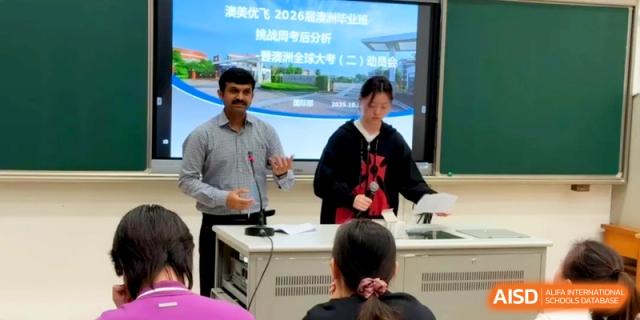 Two instructors co-present a seminar using a digital display to an audience of students and staff at Xishan Senior High School.